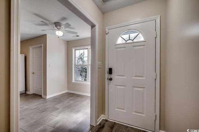 entrance foyer featuring ceiling fan, light hardwood / wood-style flooring, and a textured ceiling