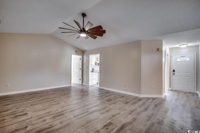 unfurnished room featuring ceiling fan, vaulted ceiling, light hardwood / wood-style flooring, and a textured ceiling