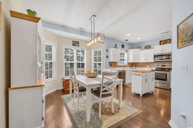 dining area featuring a healthy amount of sunlight, visible vents, and dark wood finished floors