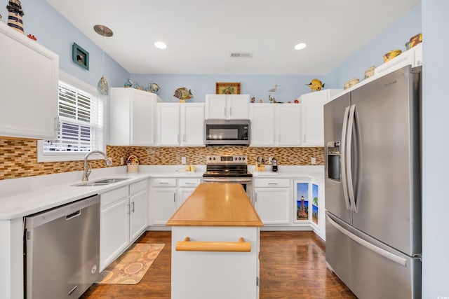 kitchen with appliances with stainless steel finishes, a center island, white cabinetry, and a sink