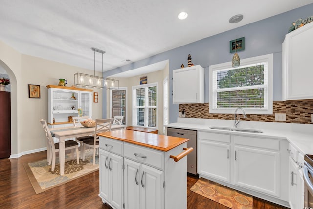 kitchen featuring arched walkways, white cabinets, stainless steel appliances, light countertops, and a sink