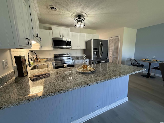 3700 Golf Colony Dr Unit 26G, Little River, SC 29566 - kitchen with appliances with stainless steel finishes, a sink, a peninsula, dark wood-type flooring, and dark stone countertops