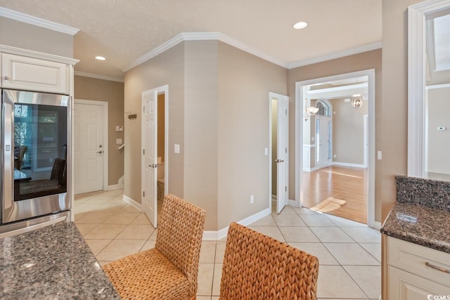 kitchen featuring white cabinetry, light tile patterned floors, ornamental molding, and stainless steel refrigerator