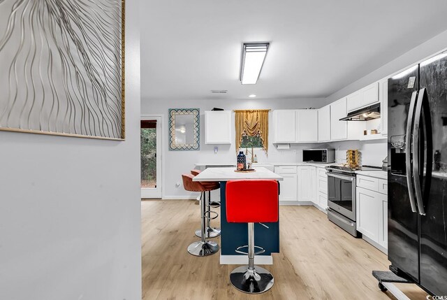 145 Bendick Ct, Little River, SC 29566 - kitchen featuring a kitchen bar, white cabinetry, under cabinet range hood, stainless steel appliances, and light wood finished floors