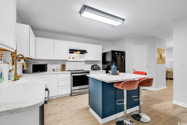 145 Bendick Ct, Little River, SC 29566 - kitchen with white cabinets, light wood-type flooring, appliances with stainless steel finishes, under cabinet range hood, and a kitchen island