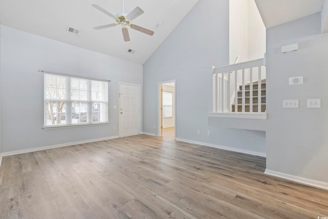 unfurnished living room with visible vents, stairway, light wood-style floors, high vaulted ceiling, and baseboards