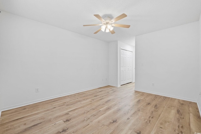 empty room featuring light wood-style floors, baseboards, and a ceiling fan