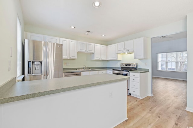 kitchen featuring under cabinet range hood, white cabinetry, stainless steel appliances, and light countertops