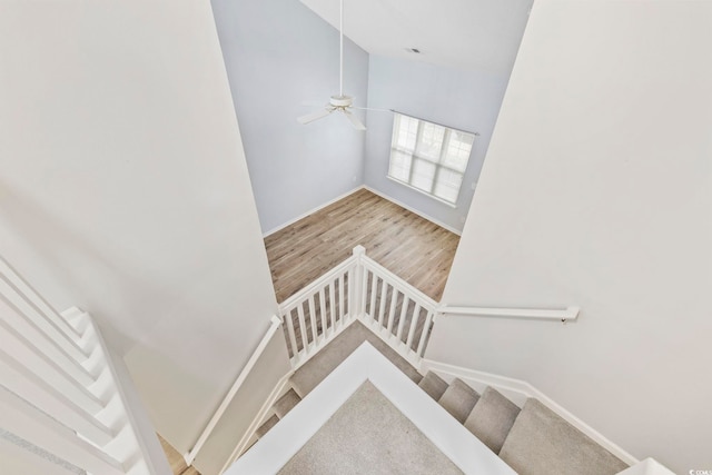 stairway featuring high vaulted ceiling, wood finished floors, and baseboards