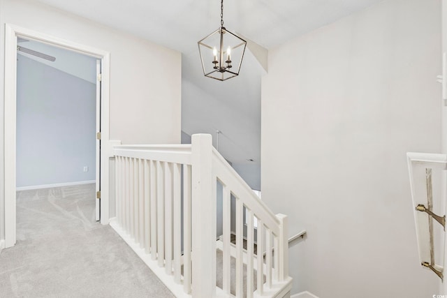 stairway featuring a chandelier, carpet flooring, and baseboards