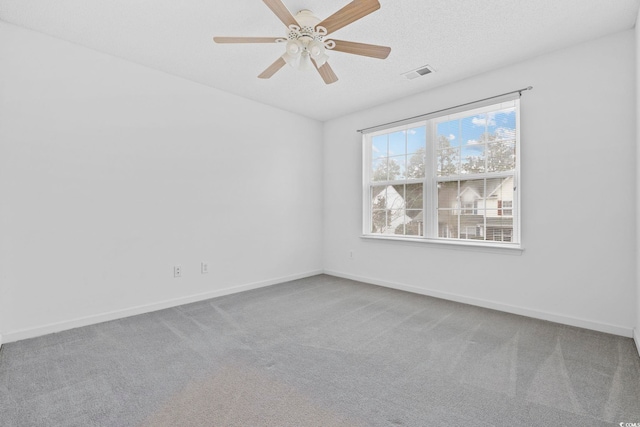 carpeted spare room with a ceiling fan, visible vents, a textured ceiling, and baseboards