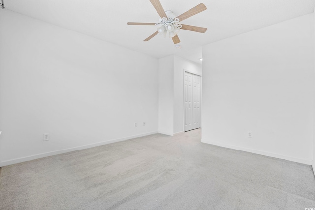 spare room with light carpet, baseboards, and a ceiling fan