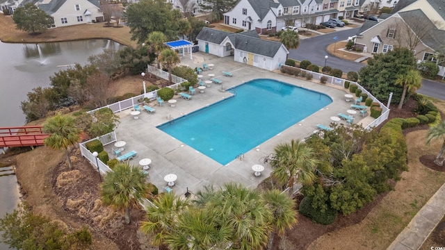 pool featuring a patio area, fence, a residential view, and a water view