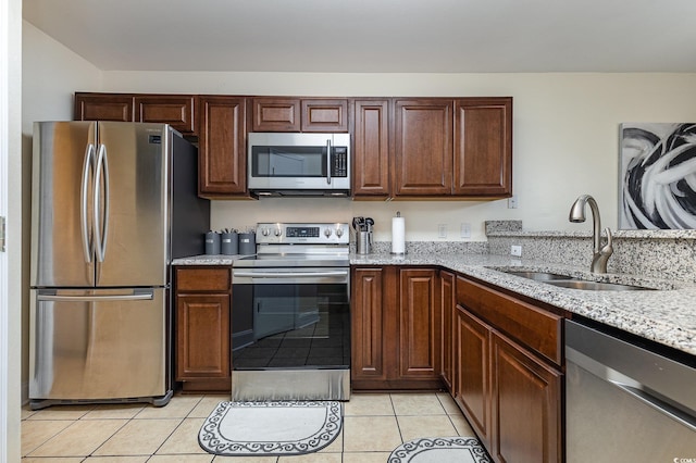 kitchen featuring stainless steel appliances, light stone countertops, sink, and light tile patterned floors