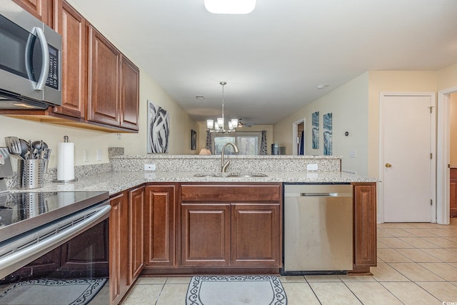 kitchen featuring sink, hanging light fixtures, stainless steel appliances, light tile patterned flooring, and kitchen peninsula