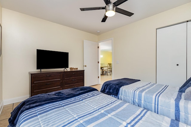 tiled bedroom with ceiling fan and a closet