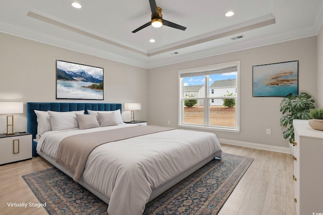 bedroom featuring crown molding, light hardwood / wood-style flooring, ceiling fan, and a tray ceiling