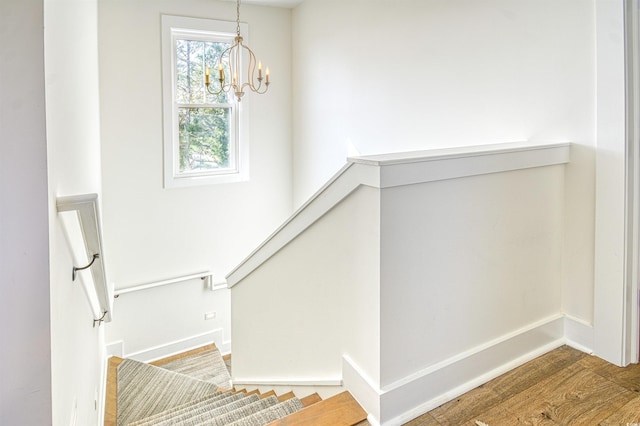 stairway featuring hardwood / wood-style flooring and a chandelier