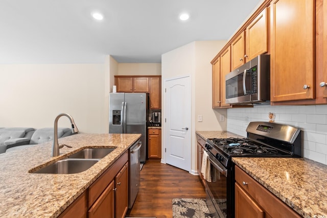 kitchen featuring stainless steel appliances, a sink, light stone countertops, dark wood-style floors, and tasteful backsplash