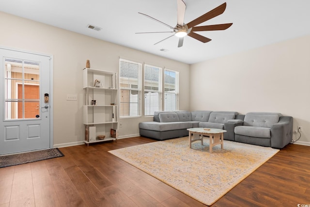 living room featuring dark wood-style floors, ceiling fan, visible vents, and baseboards