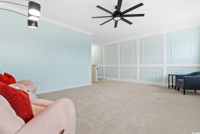 sitting room featuring baseboards, a ceiling fan, ornamental molding, carpet, and a decorative wall