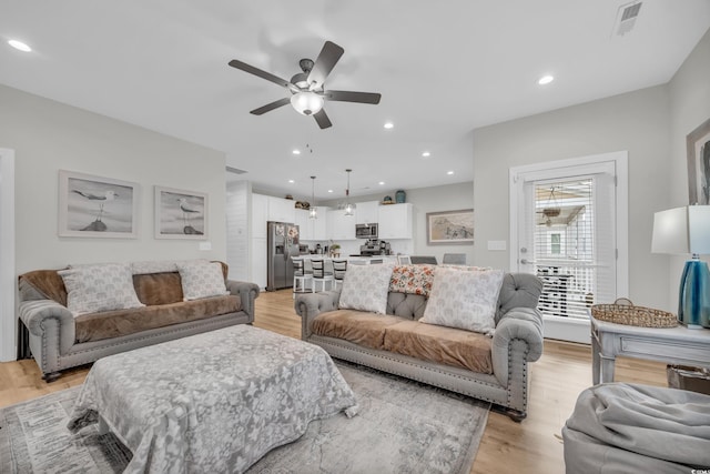 living room with ceiling fan and light hardwood / wood-style flooring