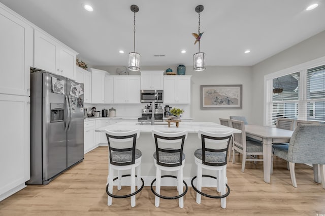 kitchen featuring pendant lighting, white cabinetry, and stainless steel appliances