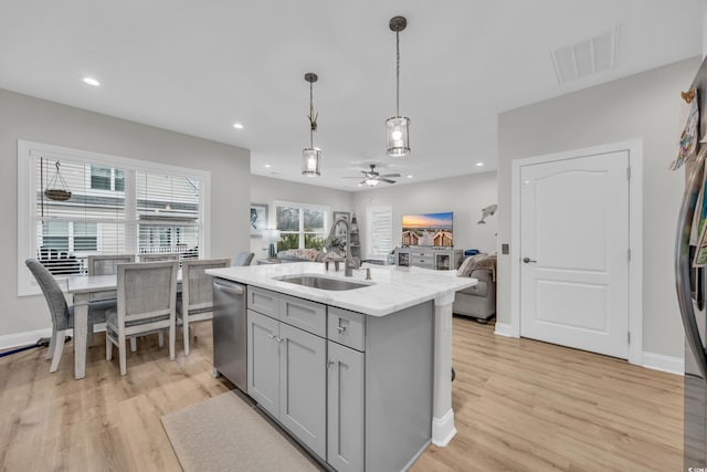 kitchen with sink, gray cabinetry, light hardwood / wood-style floors, an island with sink, and decorative light fixtures