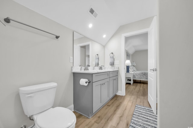 bathroom featuring vanity, hardwood / wood-style floors, vaulted ceiling, and toilet