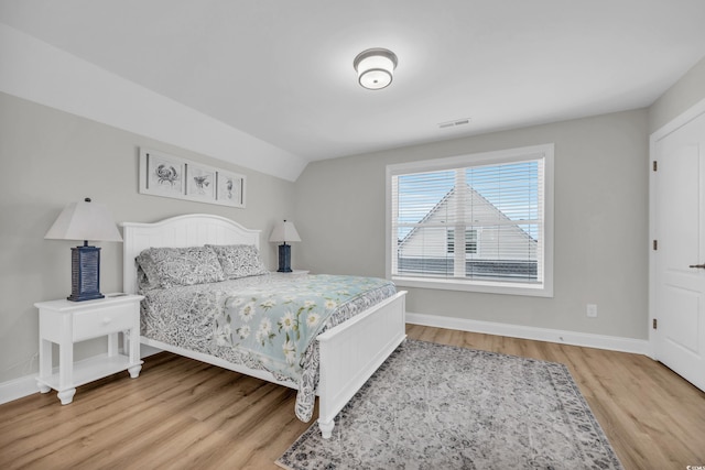 bedroom with hardwood / wood-style flooring and lofted ceiling