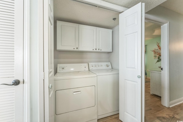 washroom featuring a textured ceiling, washing machine and dryer, cabinet space, light wood finished floors, and baseboards