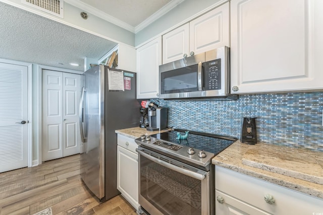 kitchen featuring visible vents, ornamental molding, appliances with stainless steel finishes, white cabinetry, and light wood-type flooring