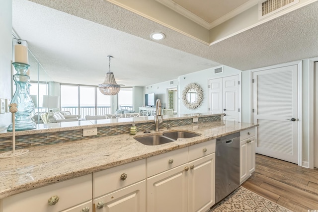 kitchen with visible vents, open floor plan, stainless steel dishwasher, white cabinets, and a sink