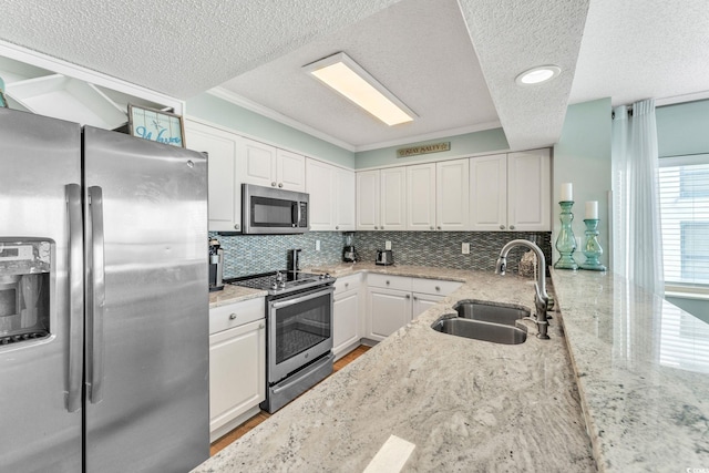 kitchen with light stone counters, a sink, white cabinets, appliances with stainless steel finishes, and backsplash