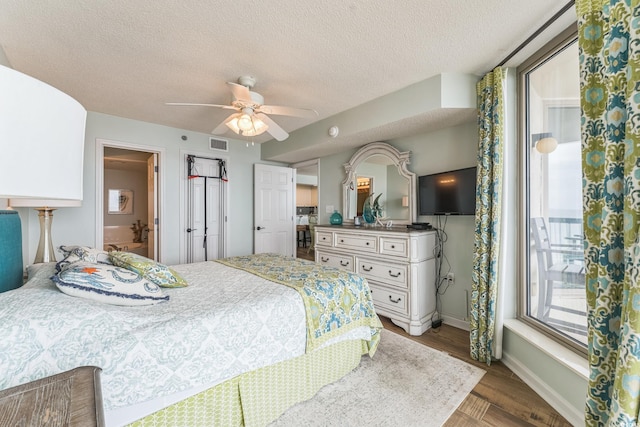 bedroom featuring visible vents, a textured ceiling, wood finished floors, baseboards, and ceiling fan