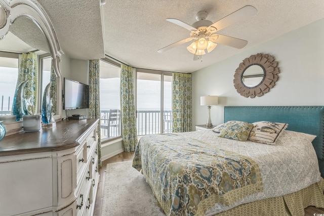 bedroom with light wood-type flooring, a textured ceiling, ceiling fan, and access to outside