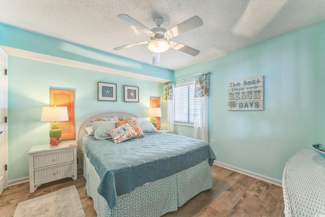 bedroom featuring a textured ceiling, baseboards, and wood finished floors