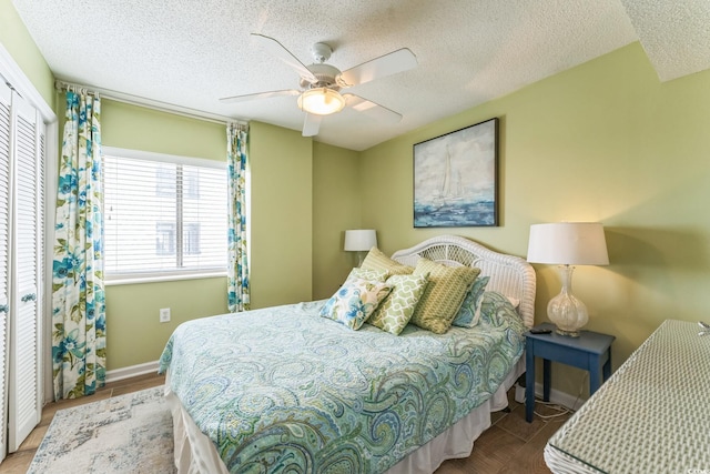 bedroom featuring a ceiling fan, baseboards, and a textured ceiling