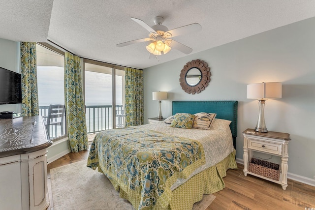 bedroom featuring wood finished floors, baseboards, ceiling fan, a textured ceiling, and access to outside