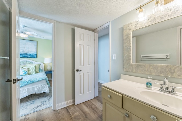 bathroom with a ceiling fan, a textured ceiling, wood finished floors, connected bathroom, and vanity