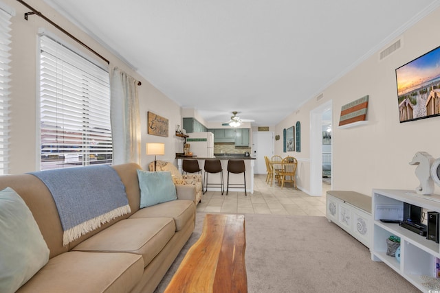 living area featuring visible vents, a ceiling fan, ornamental molding, and light tile patterned floors