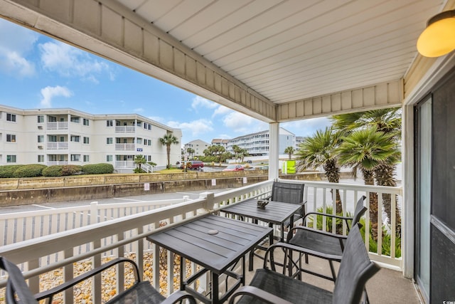 balcony with outdoor dining space and a water view