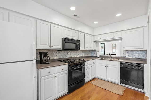 kitchen featuring tasteful backsplash, sink, white cabinets, black appliances, and light wood-type flooring