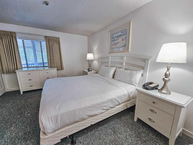 bedroom featuring dark carpet and a textured ceiling