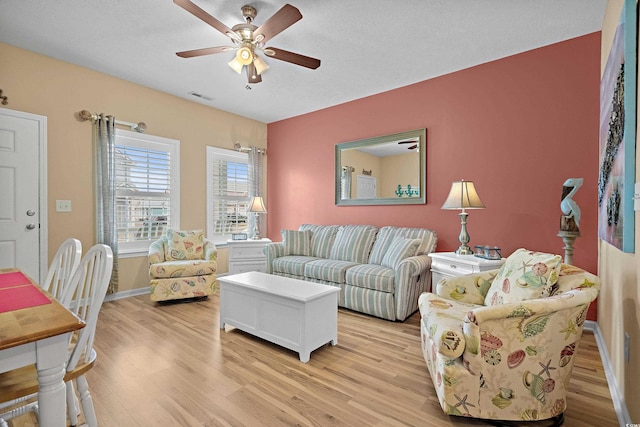 living room featuring ceiling fan, a textured ceiling, and light hardwood / wood-style floors