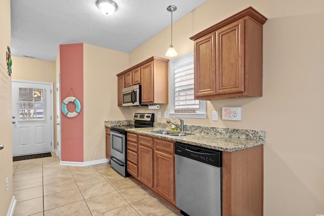 kitchen with pendant lighting, sink, appliances with stainless steel finishes, light stone counters, and light tile patterned flooring