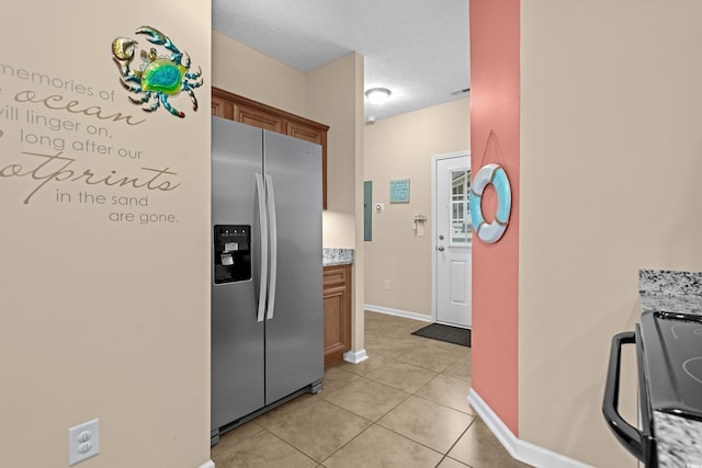 kitchen with range with electric stovetop, light tile patterned floors, a textured ceiling, and stainless steel fridge with ice dispenser