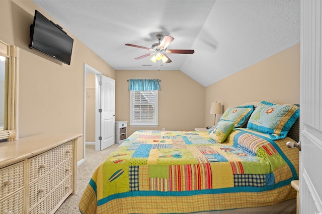 carpeted bedroom featuring ceiling fan, vaulted ceiling, and a textured ceiling