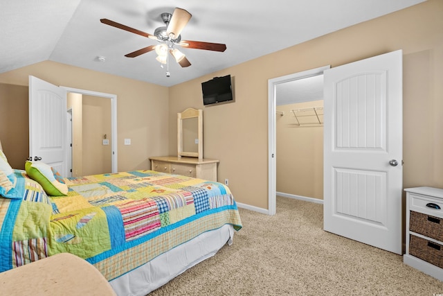 carpeted bedroom featuring vaulted ceiling, a walk in closet, ceiling fan, and a closet