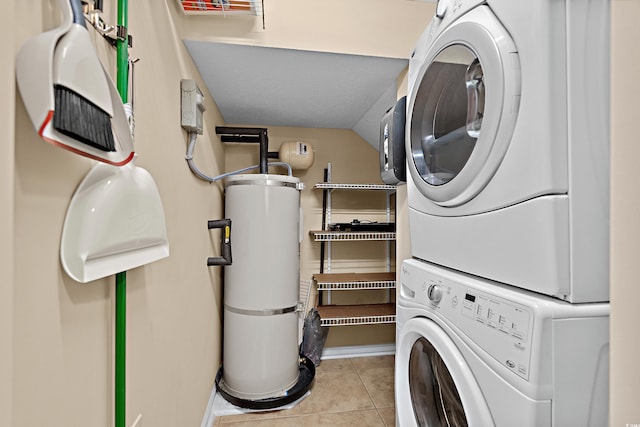 clothes washing area featuring stacked washer / drying machine, light tile patterned floors, and secured water heater